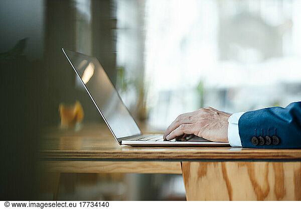 Hands of businessman working on laptop at cafe