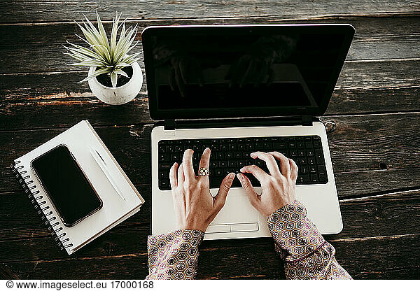 Hands of businesswoman typing on laptop at desk in office