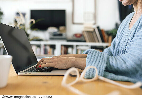 Hands of businesswoman typing on laptop sitting at table