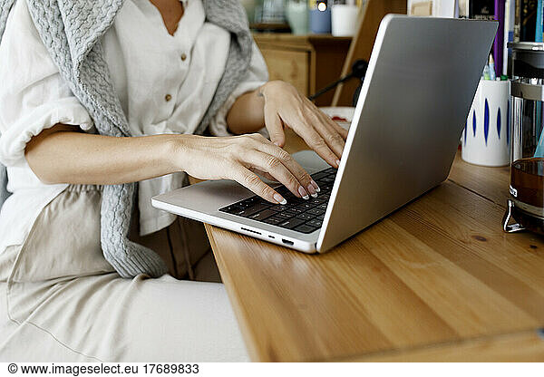 Hands of businesswoman using laptop at home