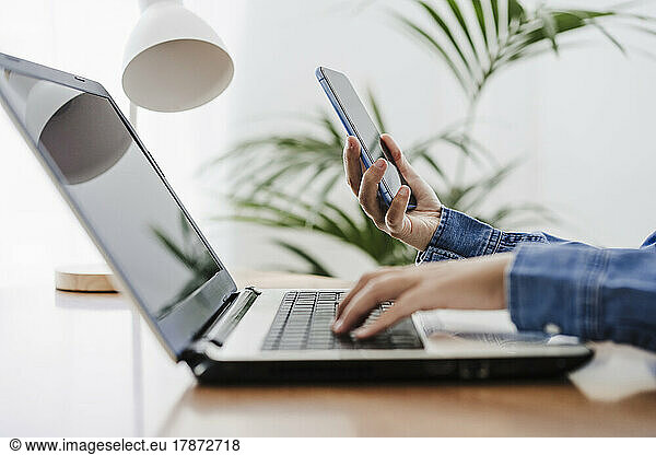 Hands of businesswoman using wireless technologies at home office