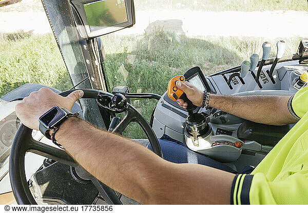 Hands of farmer driving tractor