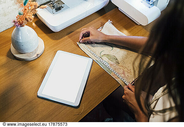Hands of fashion designer measuring cloth at workshop
