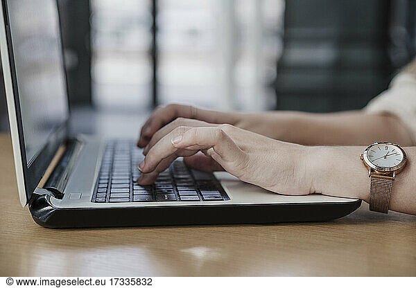 Hands of female freelancer typing on laptop in cafe