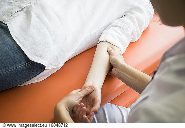 Hands of female physiotherapist massaging the arm of a woman