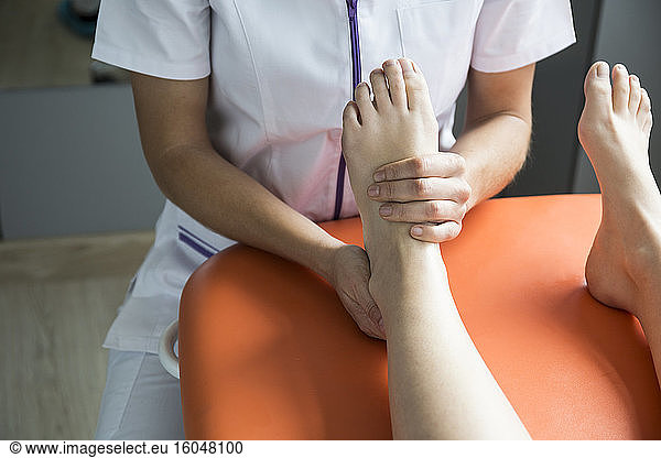 Hands of female physiotherapist massaging the foot of a woman