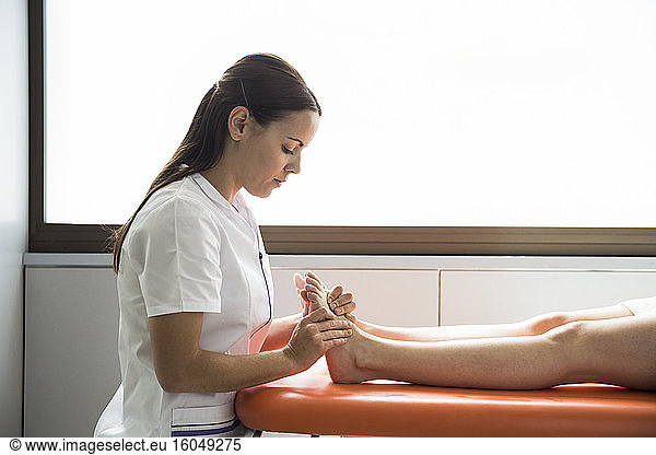 Hands of female physiotherapist massaging the foot of a woman