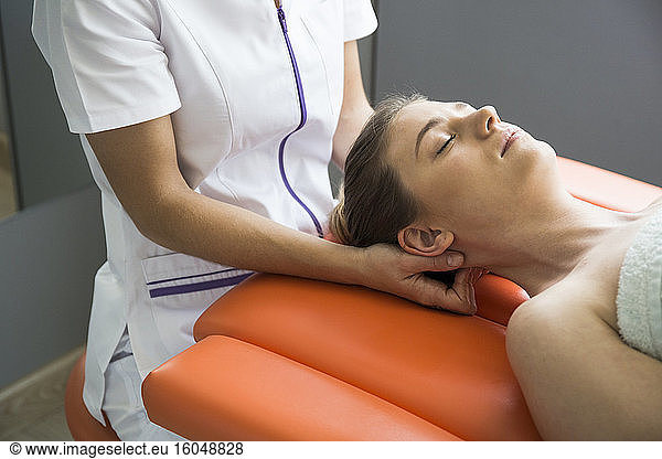 Hands of female physiotherapist massaging the neck of a woman