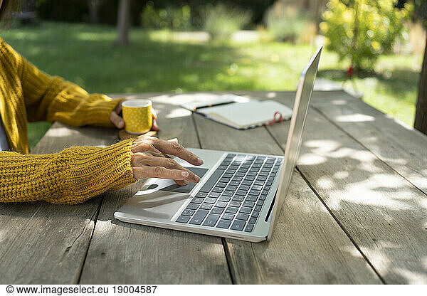 Hands of freelancer using laptop at table