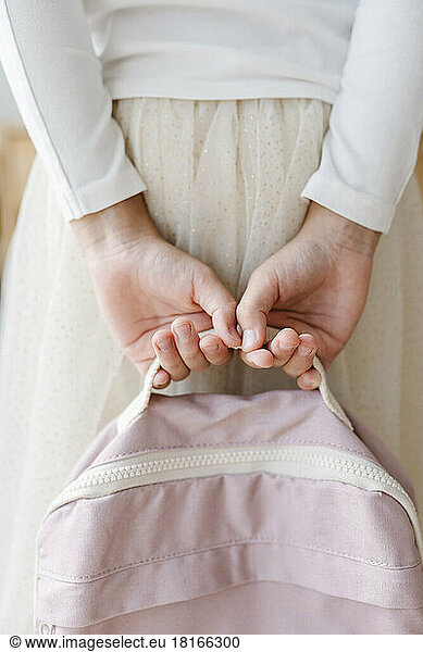 Hands of girl holding pink backpack