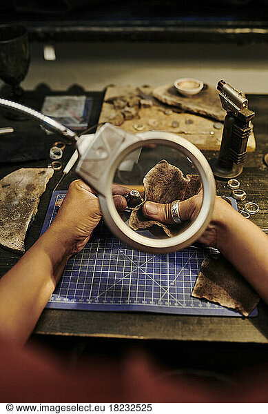 Hands of jeweller polishing golden ring with sand paper on workbench