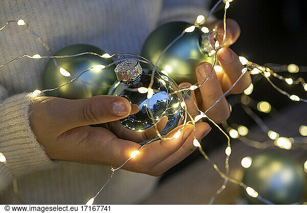 Hands of little girl holding Christmas ornaments