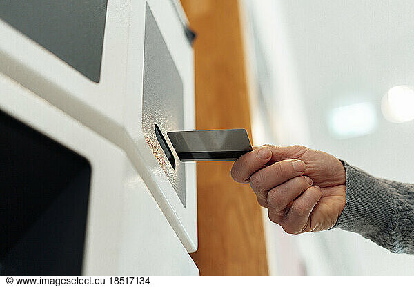 Hands of man inserting card in ATM machine