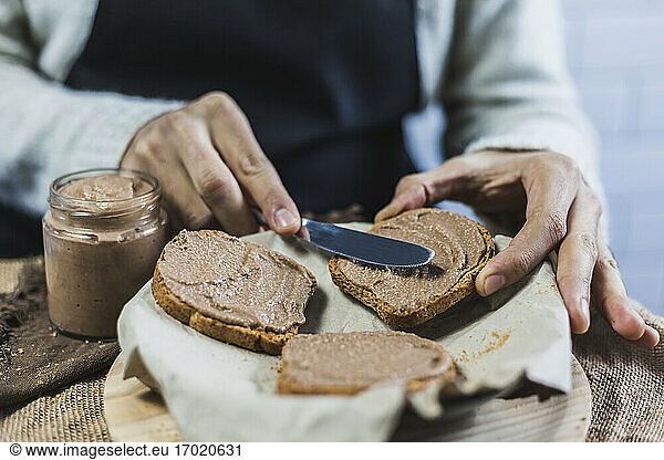 Hands of man spreading wholegrain bread slices with homemade cocoa cream