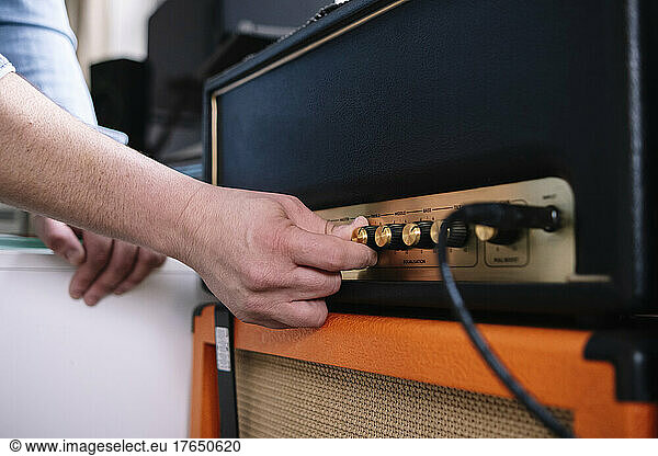 Hands of man using amplifier in home studio