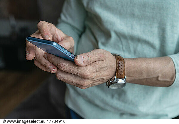 Hands of man using smart phone at home