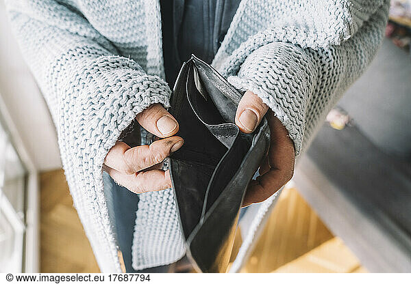 Hands of man wrapped in blanket holding empty wallet