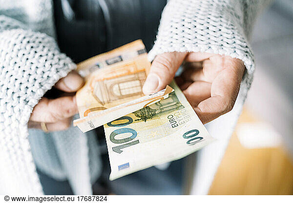 Hands of man wrapped in blanket holding Euro notes