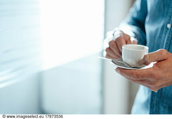Hands of mature businessman holding coffee cup