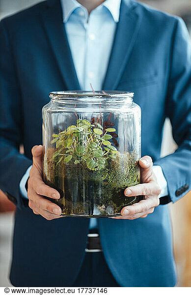 Hands of mature businessman holding glass container