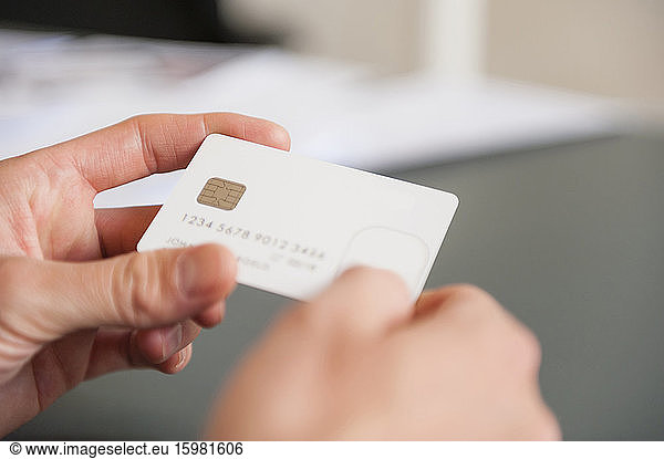 Hands of mid adult man holding blank white credit card