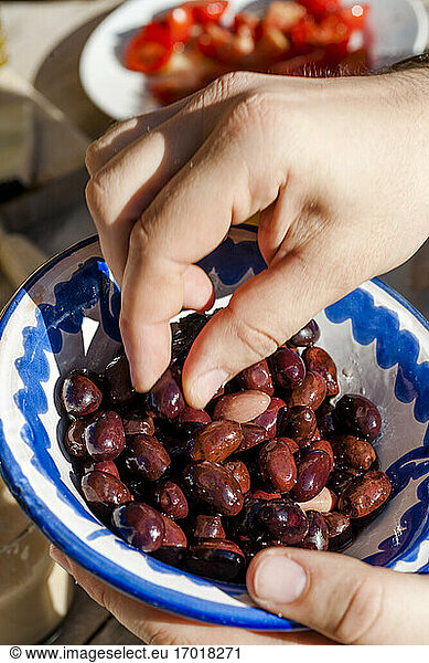Hands of person eating dates from bowl