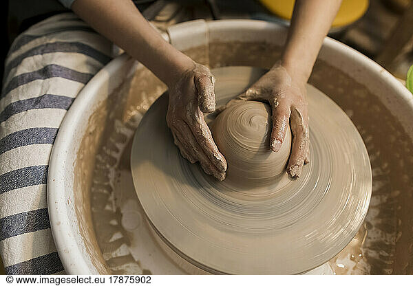 Hands of potter moulding shape on pottery wheel