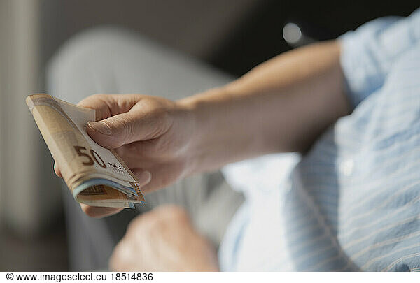 Hands of senior man with European paper Currency