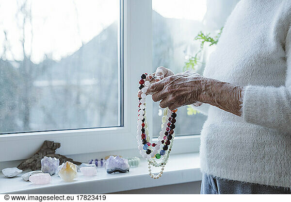 Hands of senior woman holding gemstone beads necklace