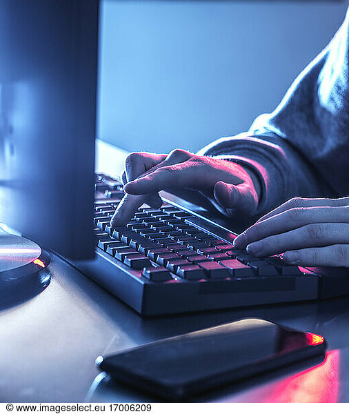 Hands of teenage boy hacking computer on desk