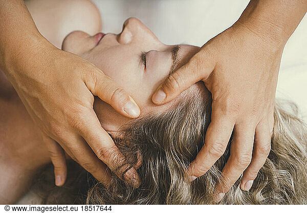 Hands of therapist giving head massage to customer in salon