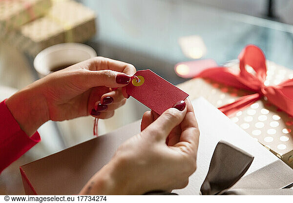 Hands of woman holding gift tag at home