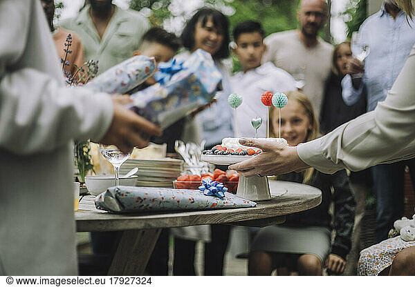 Hands of woman keeping decorated birthday cake on table
