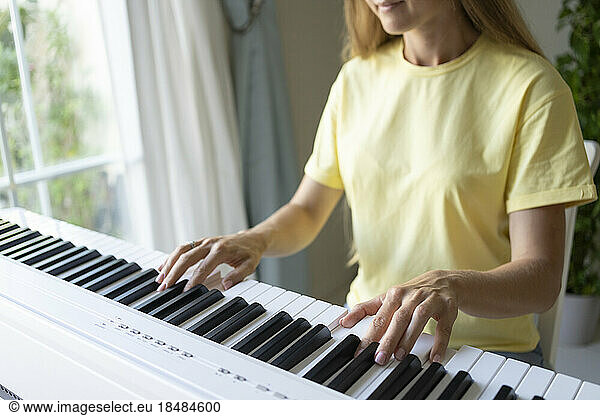 Hands of woman playing piano at home