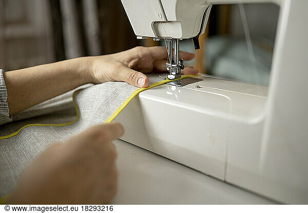 Hands of woman stitching cloth using sewing machine