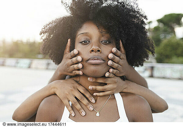 Hands touching face of Afro woman