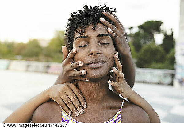 Hands touching face of woman with eyes closed