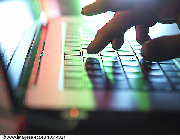Hands typing on laptop keyboard in dark at home office