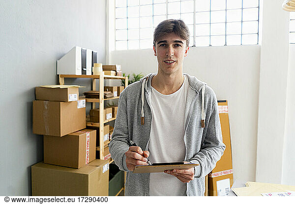 Handsome businessman with clipboard standing in distribution warehouse
