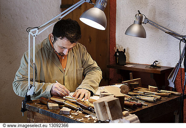 Handwerker  der in einer Werkstatt einen Entwurf für eine Figur auf einem Tisch entwirft