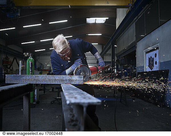 Handwerker  der mit einer Rundschleifmaschine Material schneidet  während er in einer Fabrik arbeitet