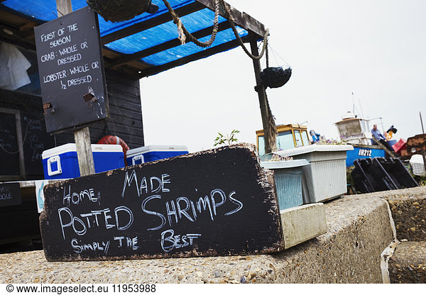 Handwritten sign advertising home made potted shrimp outside a fish shop in a Suffolk harbour.