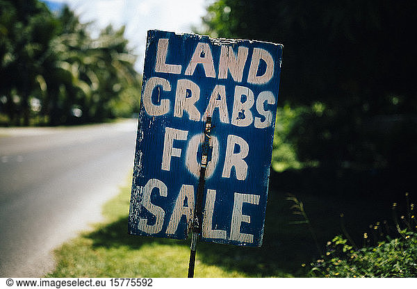 Handwritten sign by the side of road advertising land crabs for sale.