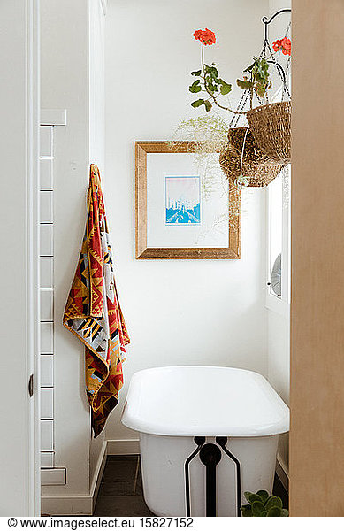 hanging flower  Pendleton towel  and a claw foot tub in white bathroom