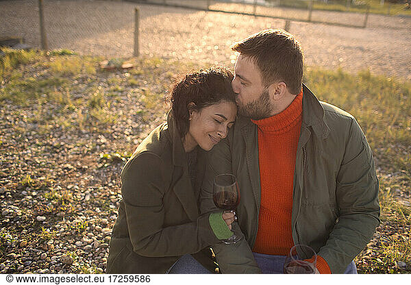 Happy affectionate couple drinking wine on sunny patio