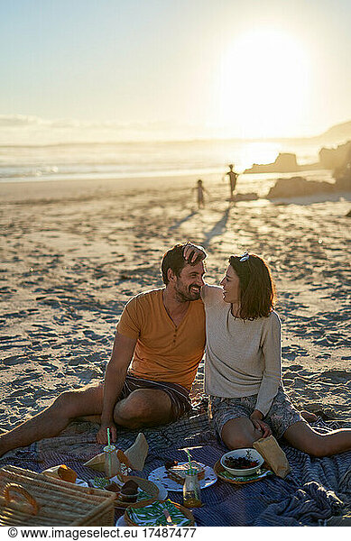 Happy affectionate couple enjoying picnic on sunny beach
