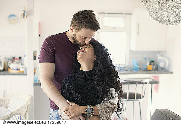 Happy affectionate couple hugging and kissing in kitchen