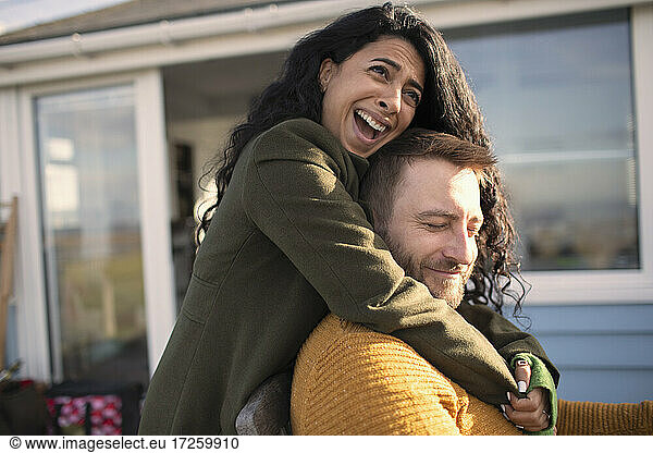 Happy affectionate couple laughing and hugging on patio