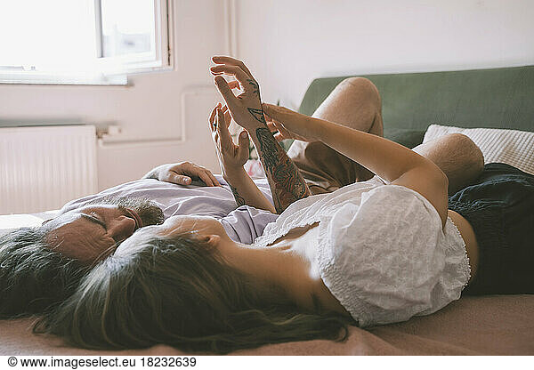 Happy affectionate hipster couple lying on bed at home