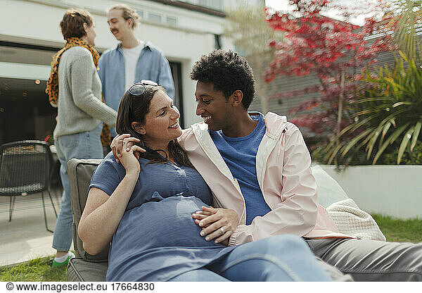 Happy affectionate pregnant couple on sunny patio